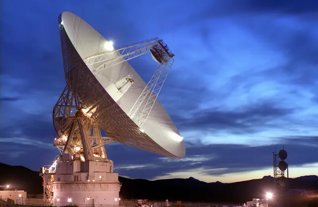Satellite ground station antenna beneath an evening sky